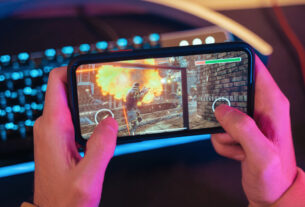 Hands of gamer playing mobile video games on his smartphone