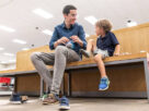 young man shopping for shoes for his son sitting in a department store bench